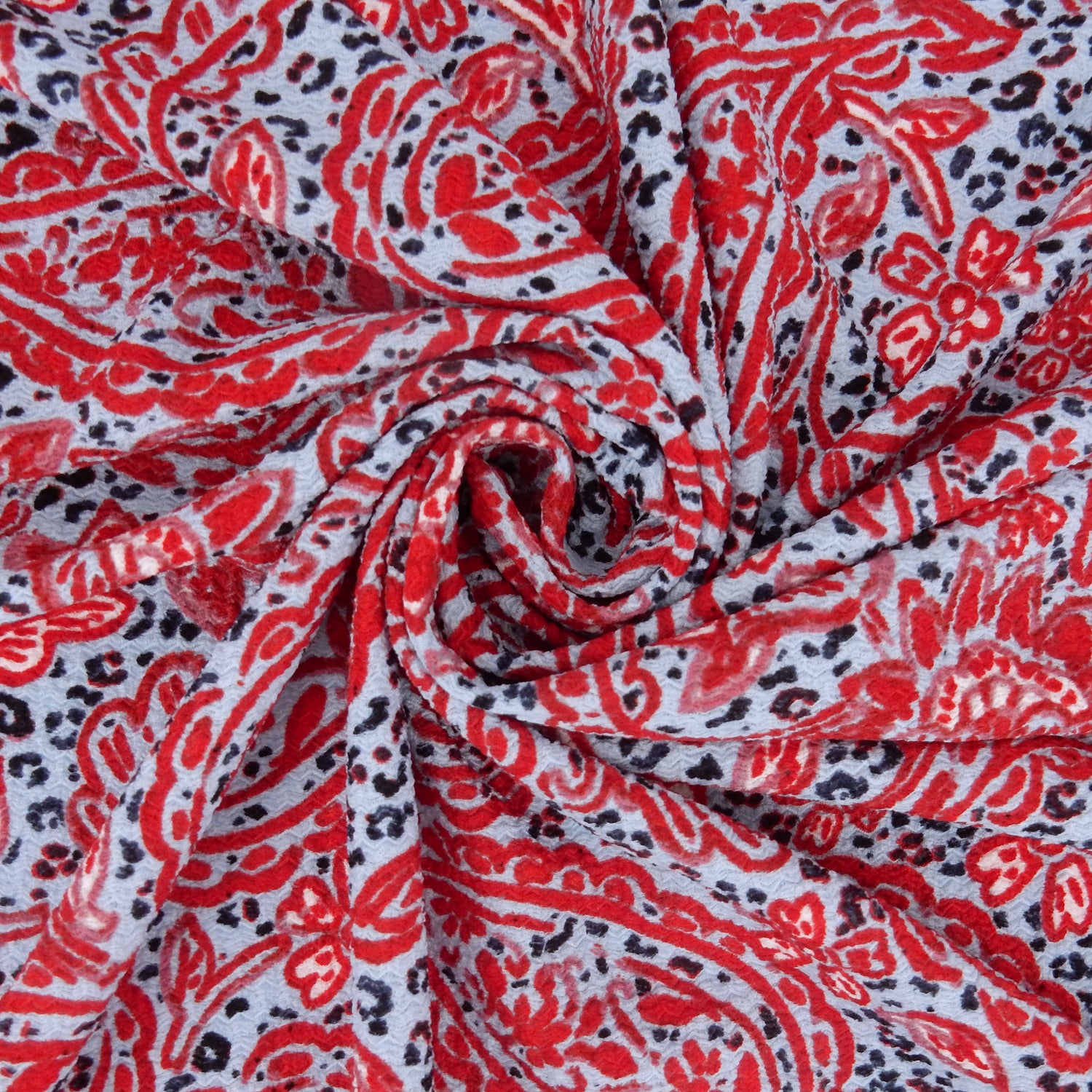 Premium textured stretch jacquard dress fabric. Luxury lightweight polyester spandex blend. Red & sky blue paisley design. shown swirled
