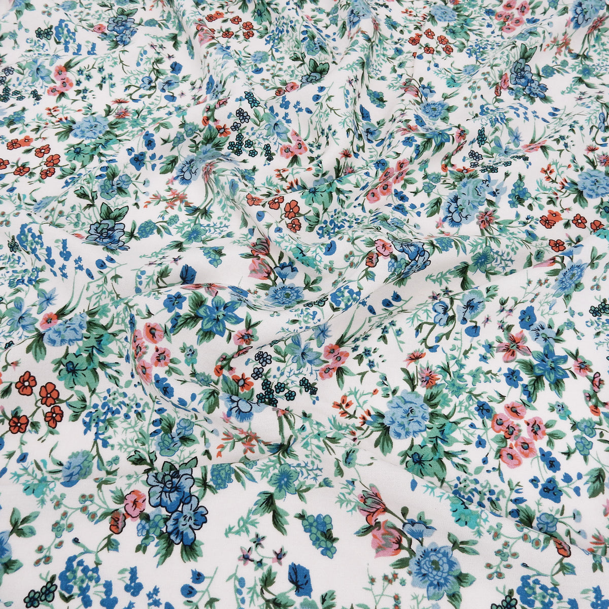 Premium 100% Rayon Challis Fabric. Playful Millefleurs Floral in Sky Blue, Terracotta, Royal Blue on Cream lightweight & ultra soft. shown lightly gathered