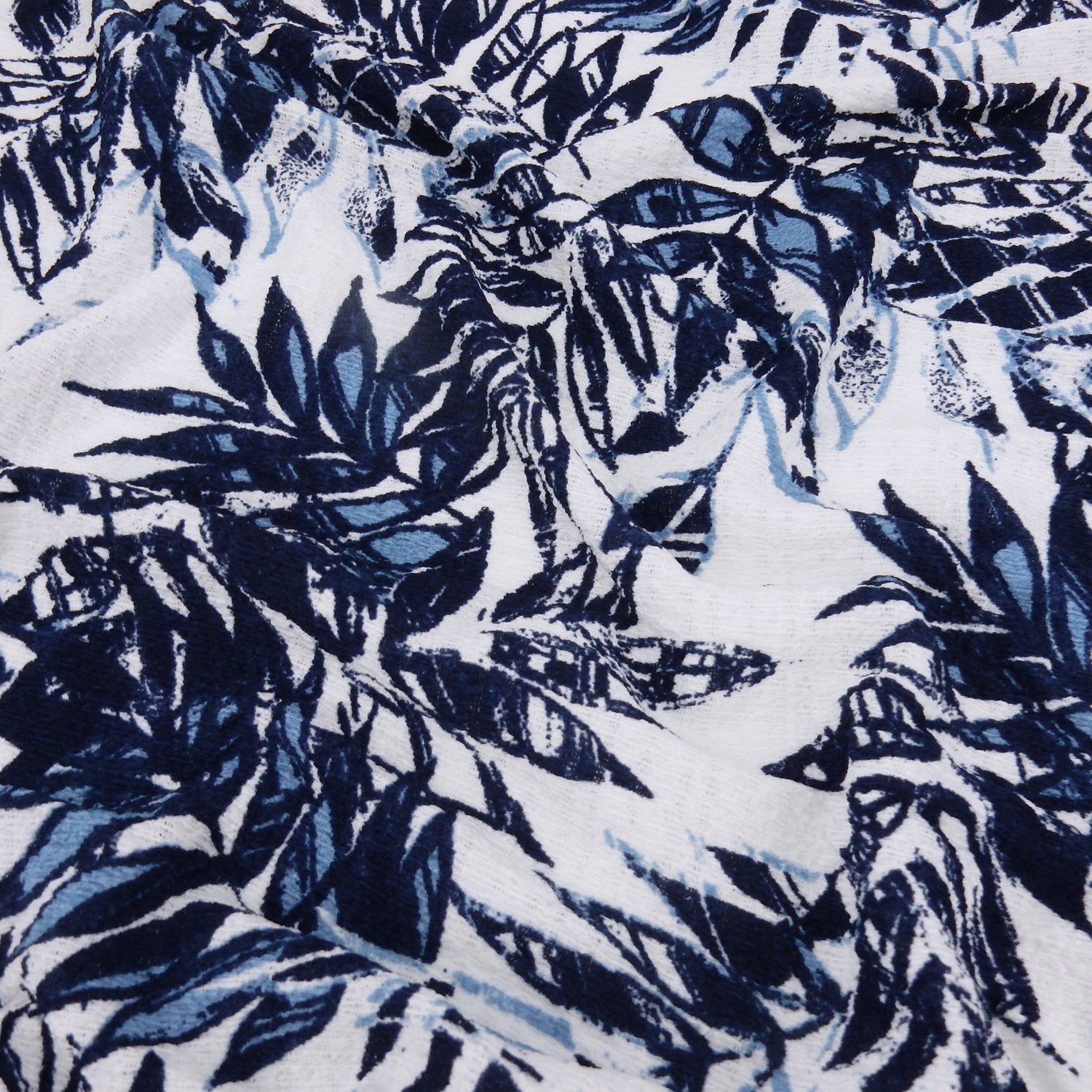 Premium  textured stretch jacquard apparel fabric. Luxury lightweight polyester spandex blend.  deep navy & breezy chambray blue tropical leaf design. shown lightly gathered