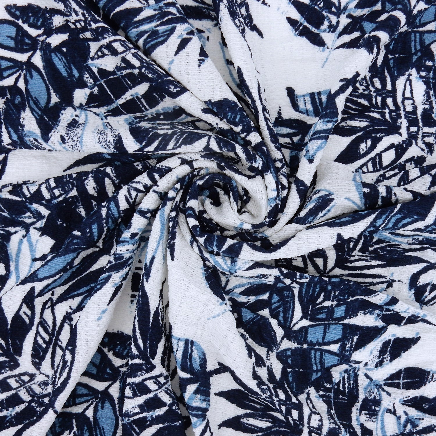 Premium  textured stretch jacquard apparel fabric. Luxury lightweight polyester spandex blend.  deep navy & breezy chambray blue tropical leaf design. shown swirled