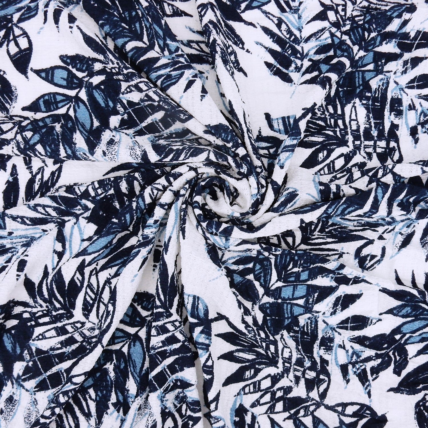 Premium  textured stretch jacquard apparel fabric. Luxury lightweight polyester spandex blend.  deep navy & breezy chambray blue tropical leaf design. shown swirled
